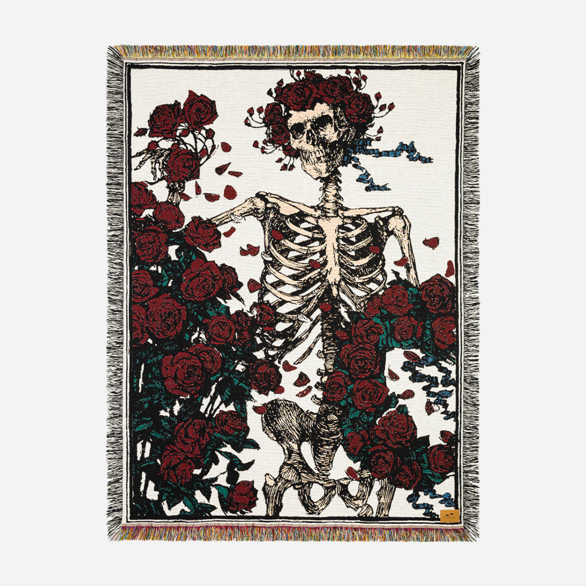 Fringed tapestry with woven skeleton and red roses design.