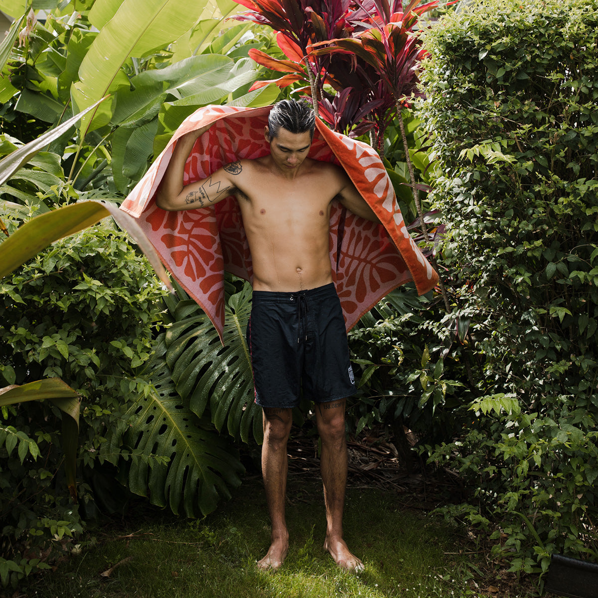 Jacquard beach towel with textured pattern in a tropical garden setting.