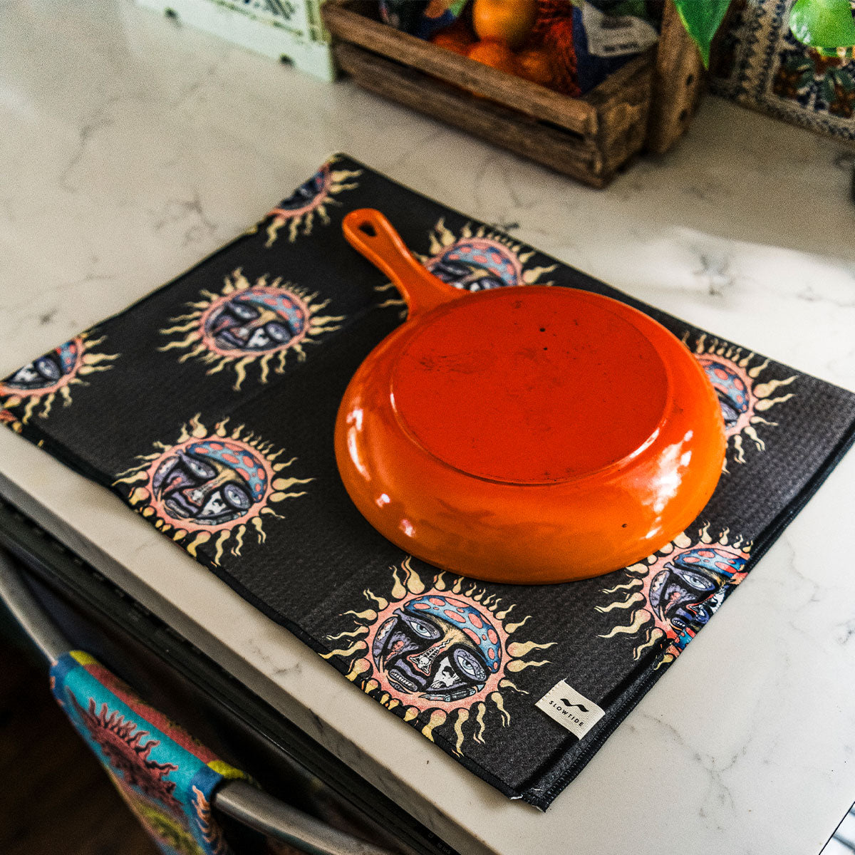 Orange pan on sun print mat next to quick-dry kitchen towel.