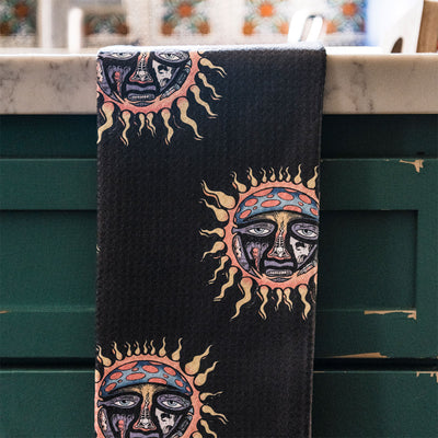Sun print towel with colorful face pattern, absorbent and quick-dry, displayed on green cabinet.