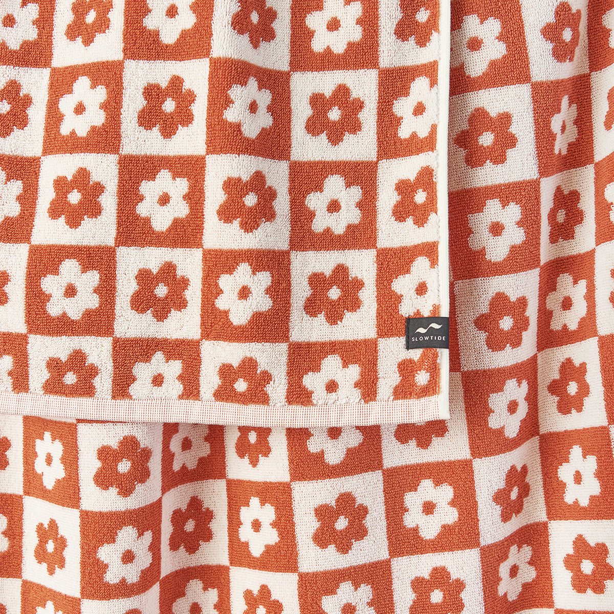 Bath towel, 100 cotton, orange and white floral geometric checkerboard pattern.