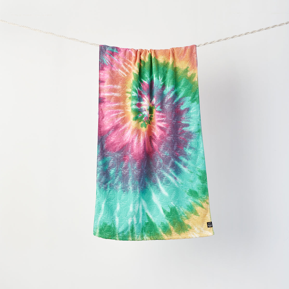 Bath towel with colorful customizable design hanging on clothesline.