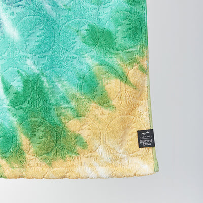Towel with green and yellow graphic design, small black label on corner.