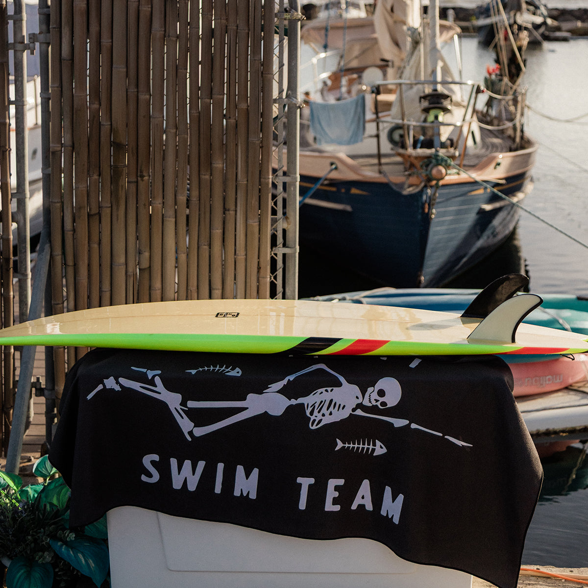 Quick-drying towel with skeleton print draped on surfboard.
