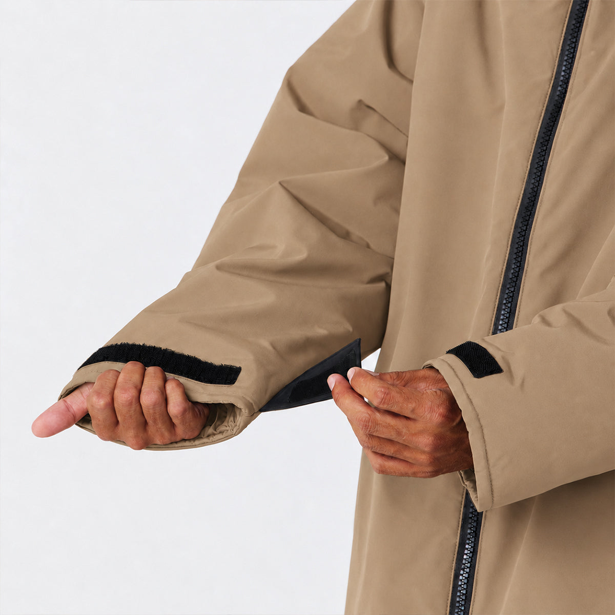 Tan all-weather parka with adjustable black Velcro sleeve strap for insulation.