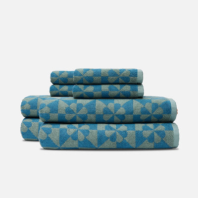 Bathroom towels with dusty blue geometric and floral pattern on white background.
