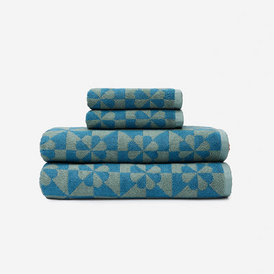 Bath towels in dusty blue with geometric patterns, stacked on a white background.
