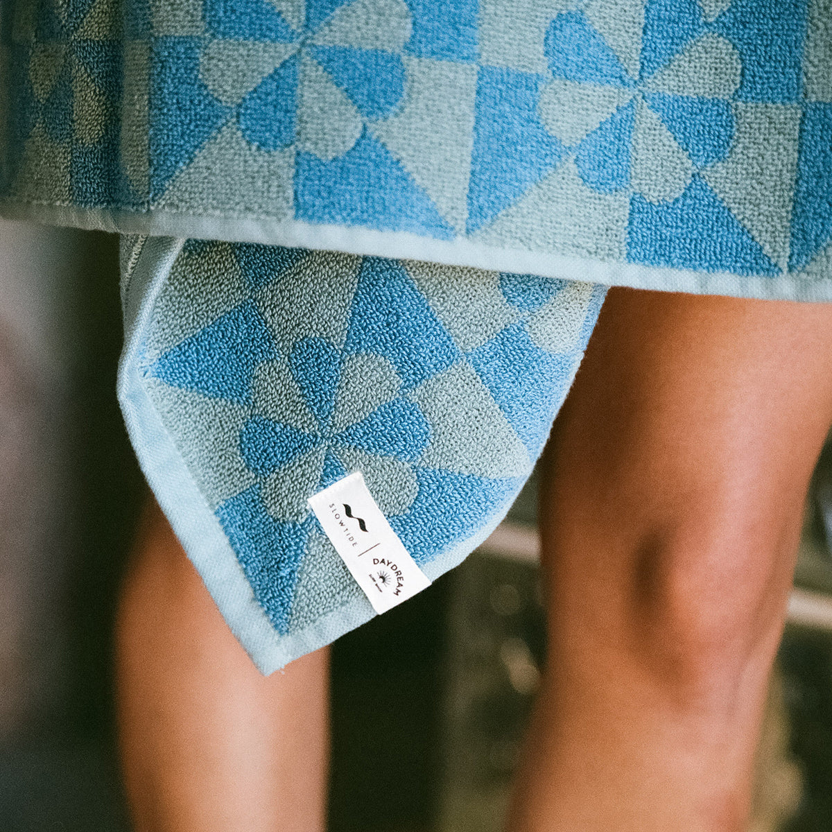 Blue geometric bathroom towel with white label, neatly draped for display.