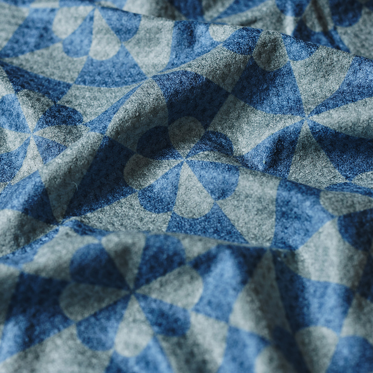 Patchwork fabric with blue and gray heart and triangle patterns, quilted cotton texture.
