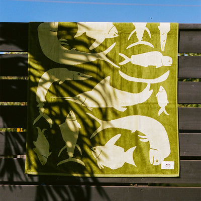 Velour towel with white fish and whale print on dark wood fence.