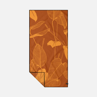 Beach towel with rust-orange color and yellow tropical leaf pattern.