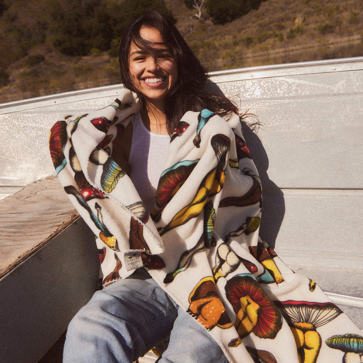 Polar fleece blanket with colorful mushroom-butt print shown outdoors.