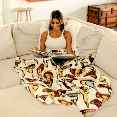 Polar fleece blanket with mushroom-butt print draped on a couch.