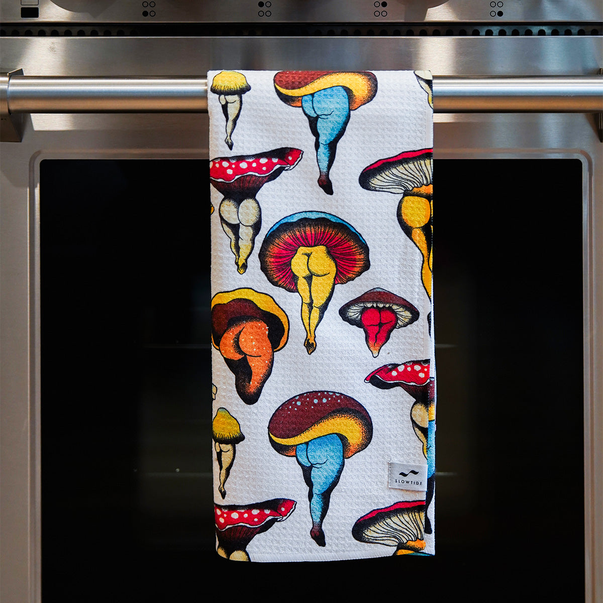 Dish towel with colorful mushroom pattern on oven handle.