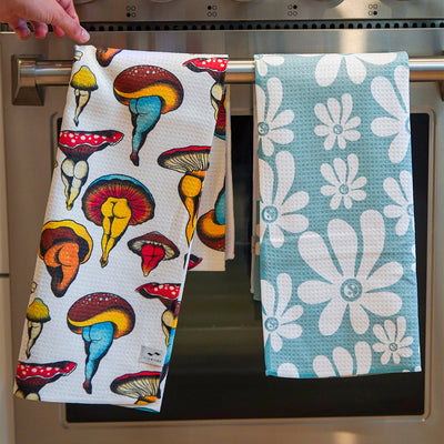 Kitchen towels, eco-friendly cotton, mushroom and white flower patterns, hanging on oven handle.