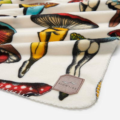 Polar fleece blanket with colorful mushroom-butt print and stitched leather corner label.