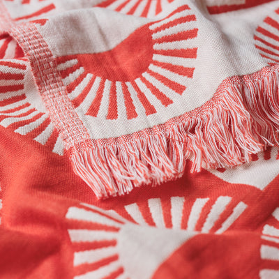 Turkish towel, lightweight cotton with red and white sunburst pattern, fringed edges.