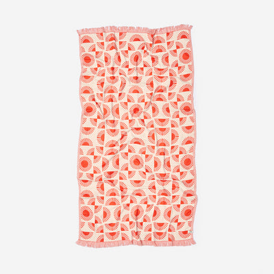 Turkish towel with red and white geometric sunburst pattern and fringe edges.