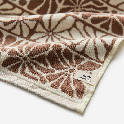 Bath towel, brown and cream cotton with floral stripe pattern and label on edge.