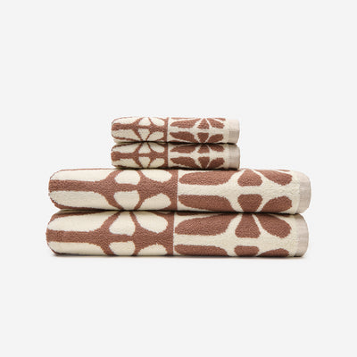 Geometric bath towels, cotton, brown and cream abstract patterns, folded on white background.