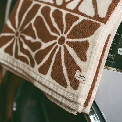 Bath towel with brown and white floral pattern draped on washing machine.