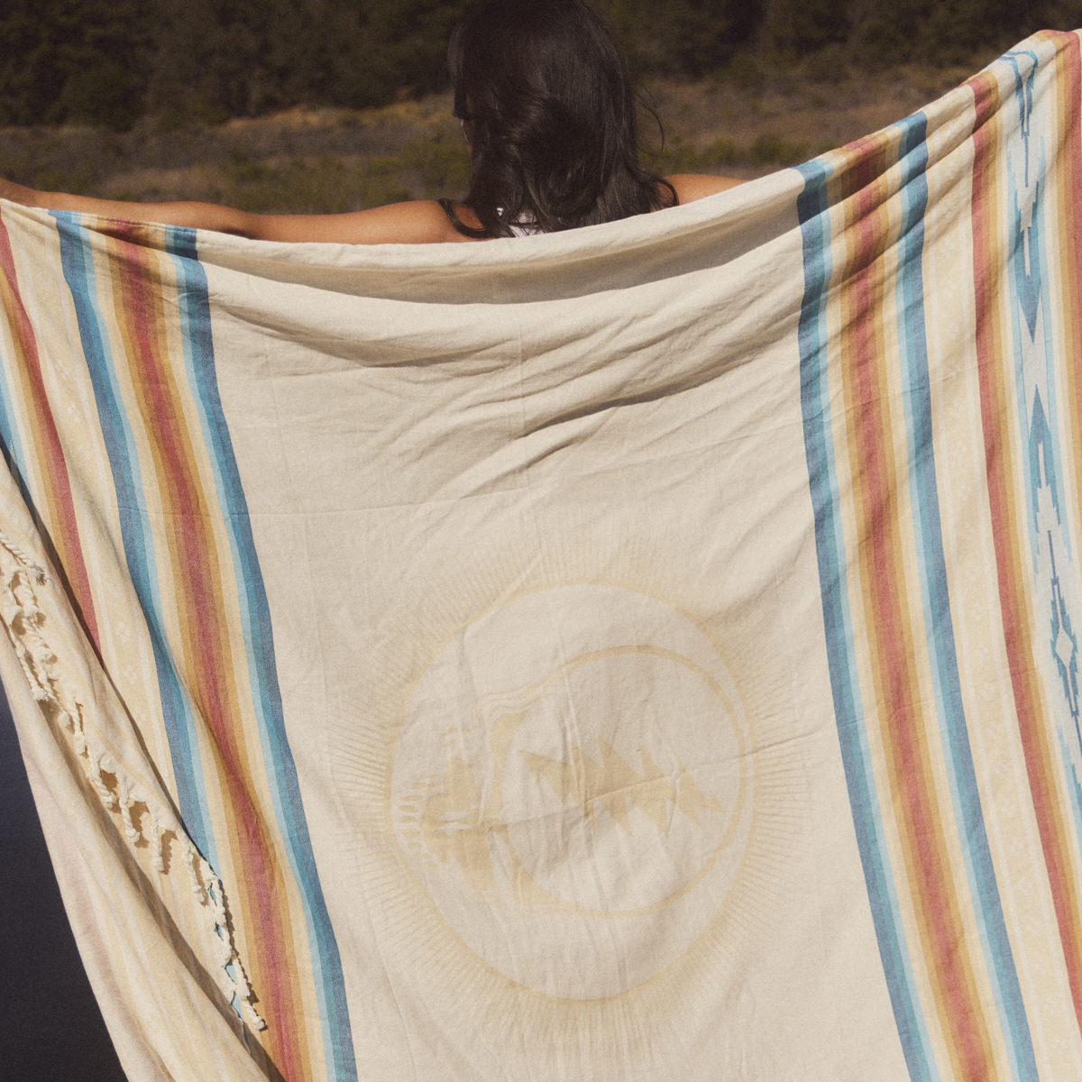 Oversized cotton blanket with striped pattern displayed outdoors.