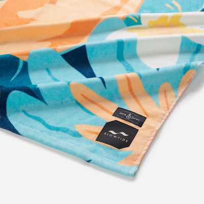 Cotton towel with colorful pattern and two labels on the corner, close-up view.