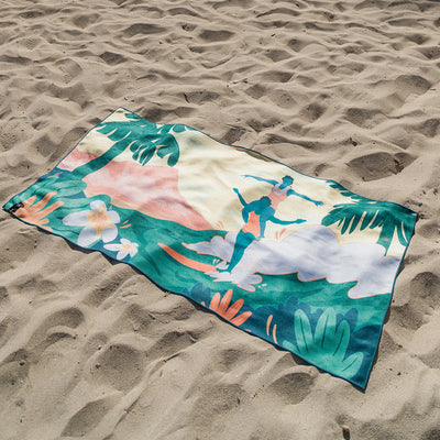 Quick-drying towel with colorful surfing design on sand.