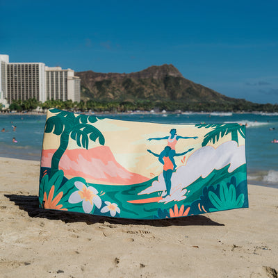 Travel towel with vibrant tropical beach and surfer pattern, city and mountains in design.