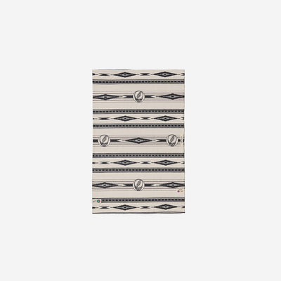 Beige blanket with vintage-style black and grey patterns on soft white fabric.