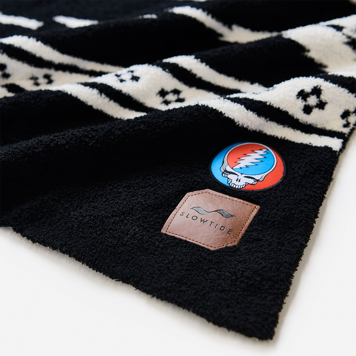 Throw blanket with black and white pattern and skull logo patches.