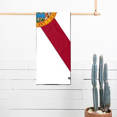 Beach towel with Florida flag design, fast-drying fabric, displayed on wooden rack.