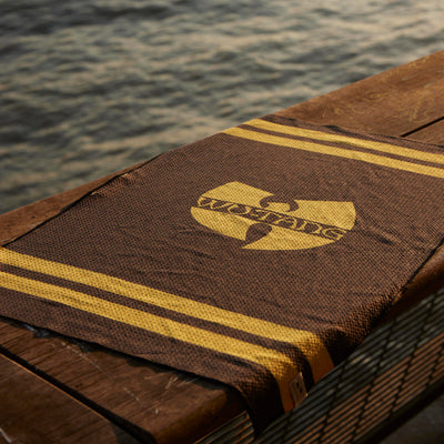 Brown eco-friendly kitchen towel with yellow stripes and logo, displayed on wood outdoors.