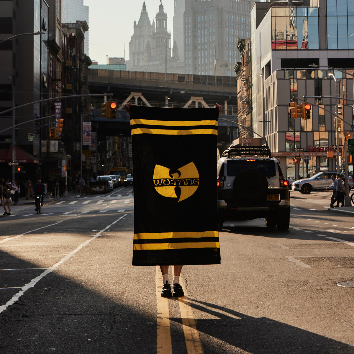 Flag with bold graphic and large velour towel displayed outdoors near city buildings.