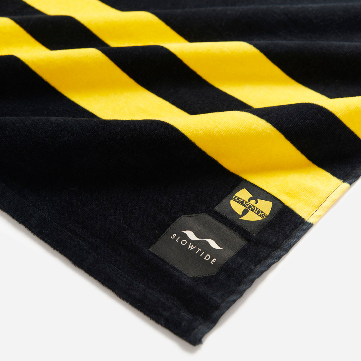 Velour beach towel with black and yellow stripes and small logos in the corner.
