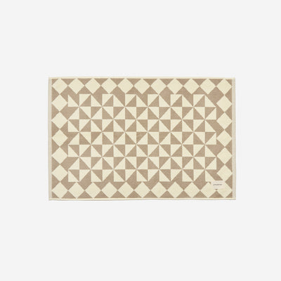 Cotton bath mat with beige and cream geometric triangle and diamond pattern.