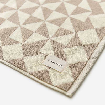 Beige bath mat with geometric triangle pattern.