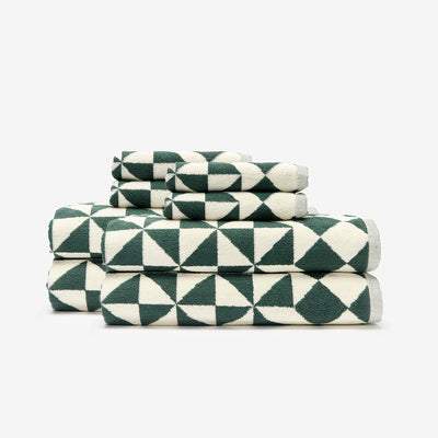 Bath towels with green and white geometric pattern stacked neatly.