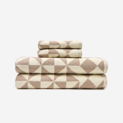 Cotton towels with beige and cream geometric triangle pattern, stacked.