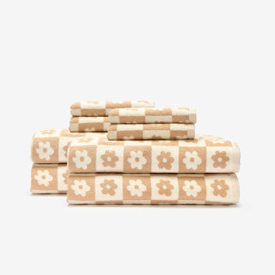 Floral checkerboard cotton towels stacked, sustainably sourced.