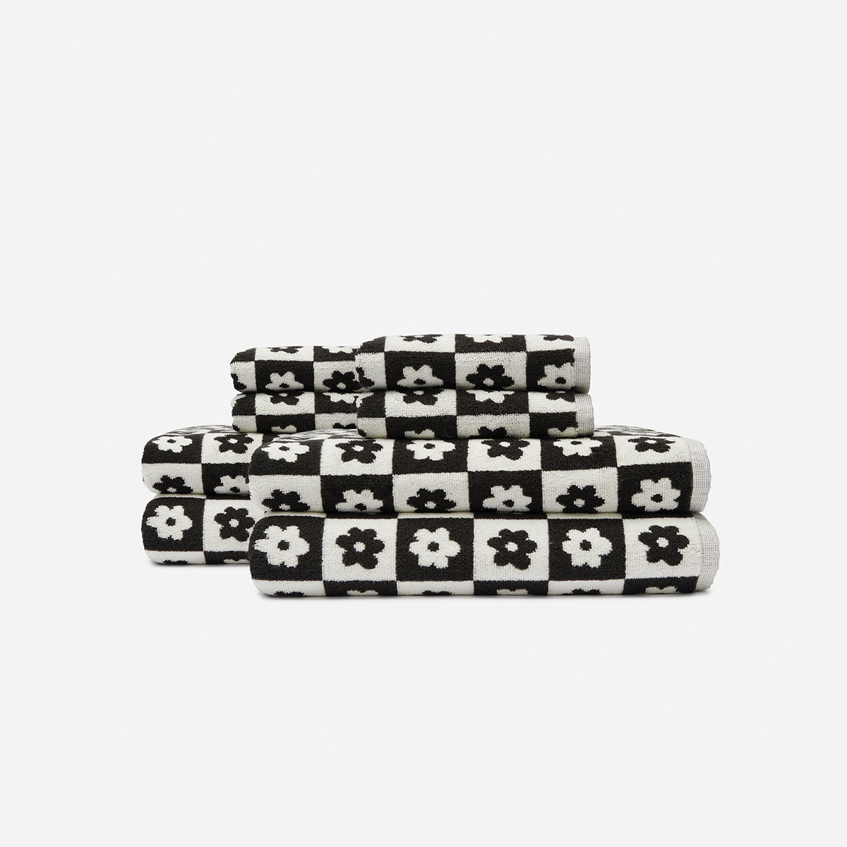 Bath towels with black and white checkered pattern and floral design, stacked.