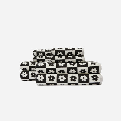 Bath towels with black and white checkered pattern and floral design, stacked.