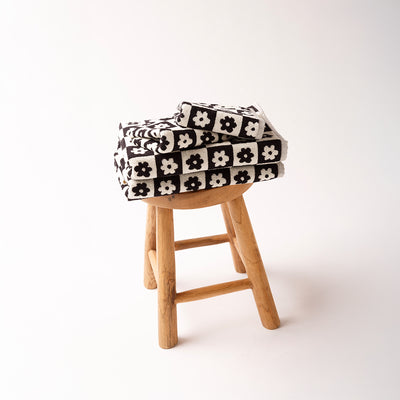 Bath towels with black and white pattern folded on a wooden stool.
