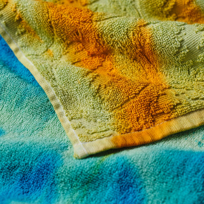Bath towels, cotton, customizable colors in yellow, green, and blue stacked together.