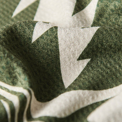 Kitchen towel with green and white abstract pattern, textured fabric, close-up view.
