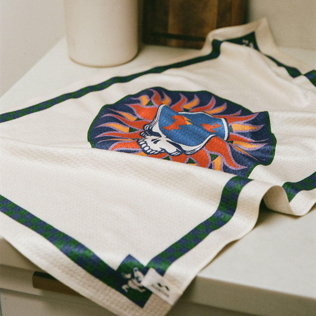 Eco-friendly kitchen towel with flaming skull and cap, green and blue border.