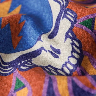 Kitchen towel with white skull design and bold multicolor patterns.