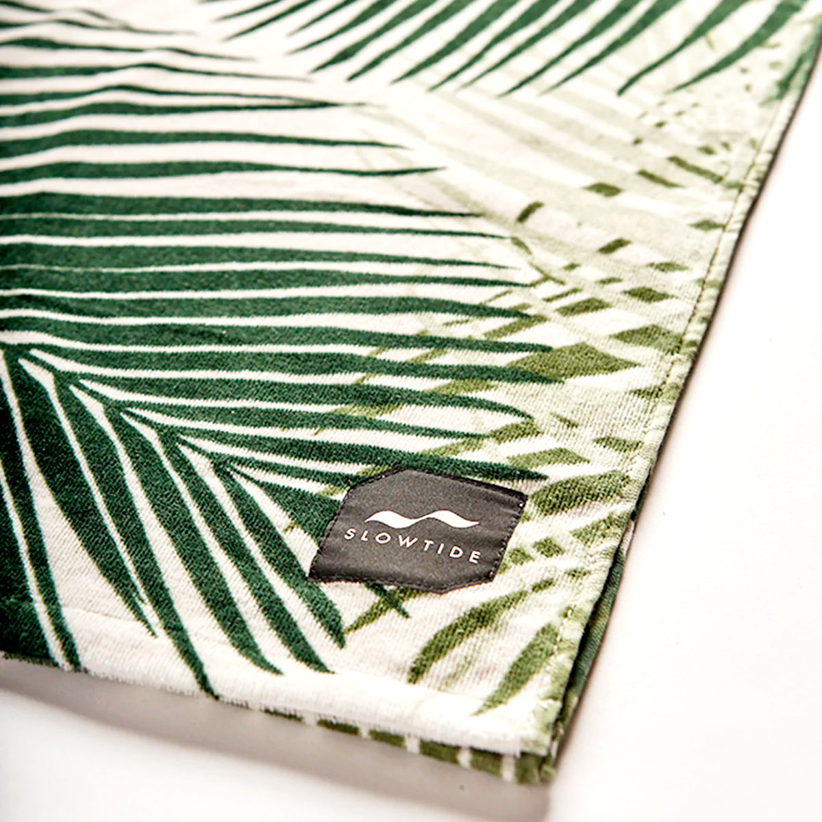 Velour towel with green and white print, corner label visible.