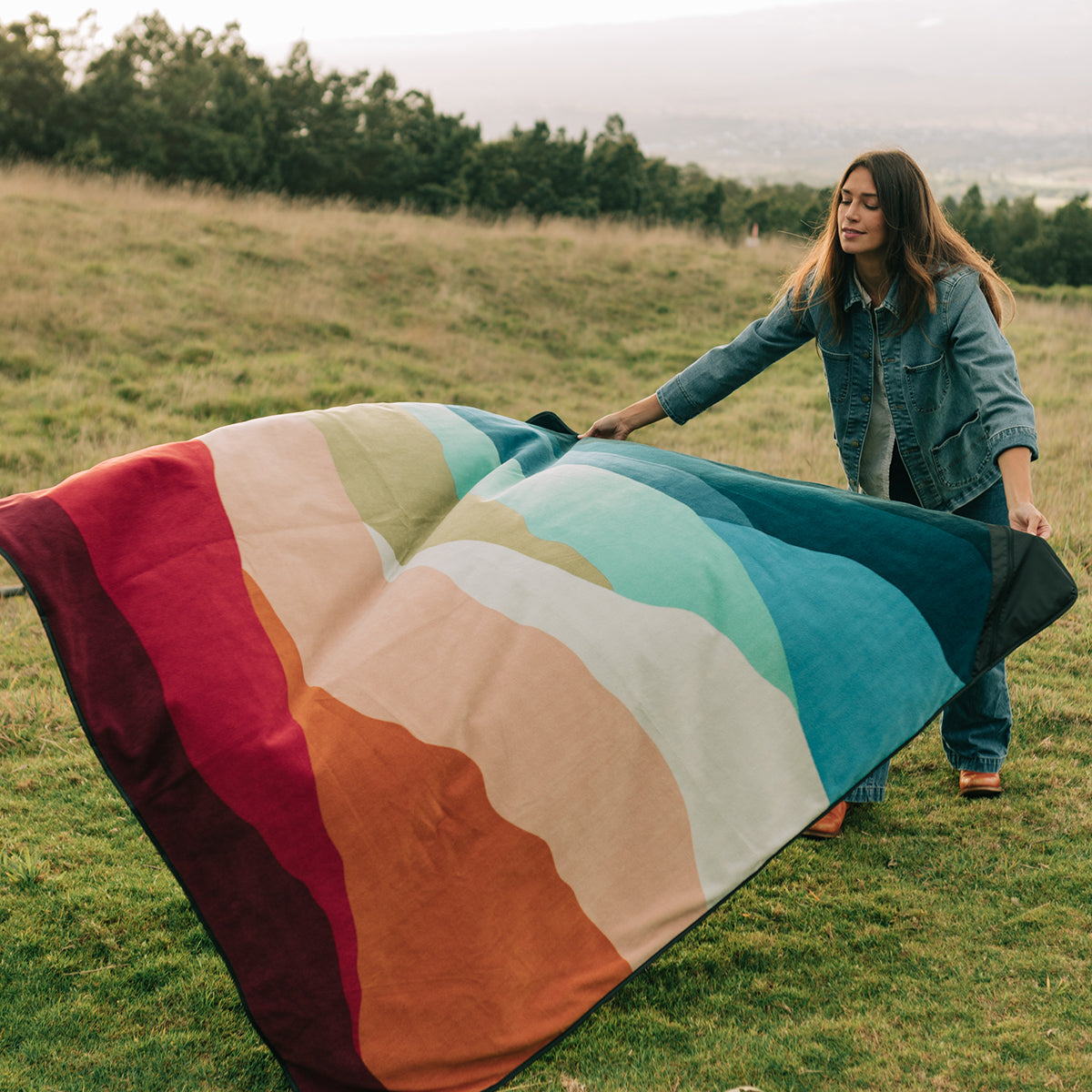 Outdoor blanket made of recycled materials featuring a multicolor striped landscape design.