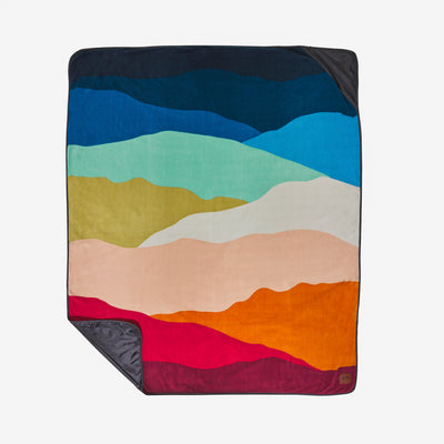 Water-repellent outdoor blanket with a multicolored layered mountain landscape pattern.